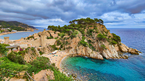 istock Beautiful panoramic view of Tossa de Mar fortification, rocky cliffs, trees and Es Codolar beach. Turquoise water of the Mediterranean Sea. Costa Brava, Catalonia, Spain 2178022659