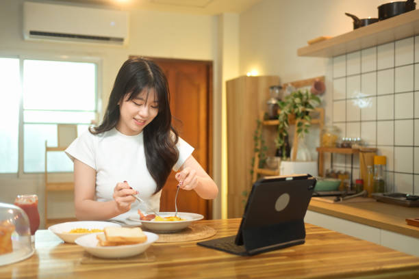 istock Attractive young woman enjoying her breakfast and using digital tablet at a kitchen table 2178040373