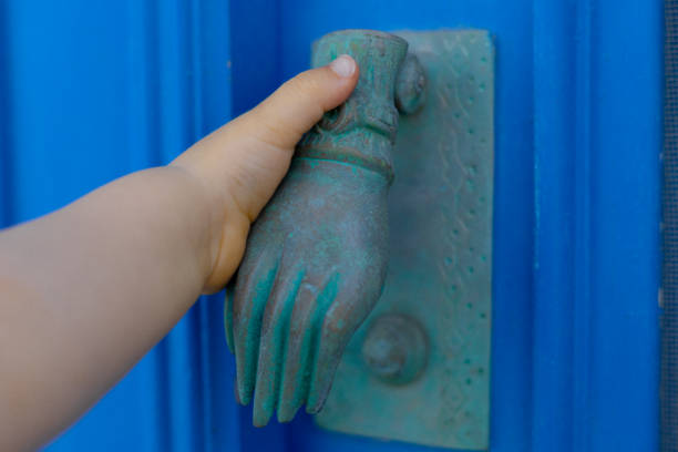 baby holding an unusual blue door knocker in form of a hand