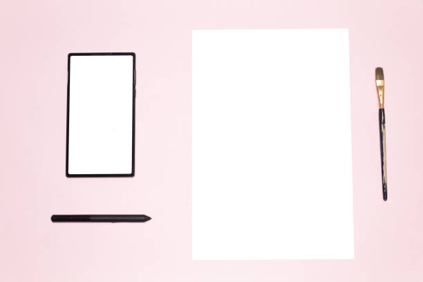 A tablet with a blank screen and its respective stylus next to a blank canvas with a worn brush on a pink background. Technology and creativity. Combination between digital and manual.