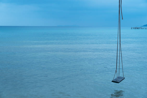 lonely wood swing with blue sea background