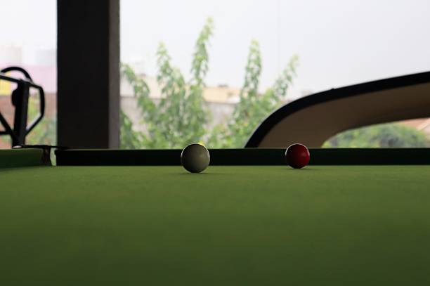 Billiards is a family of games played on a rectangular table with a designated number of small balls and a long stick called a cue. The table and the cushioned rail bordering the table are topped with a felt-like tight-fitting cloth.