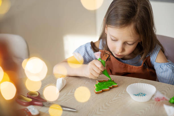 istock A little girl decorates a Christmas gingerbread mitten with tree. 2178050162