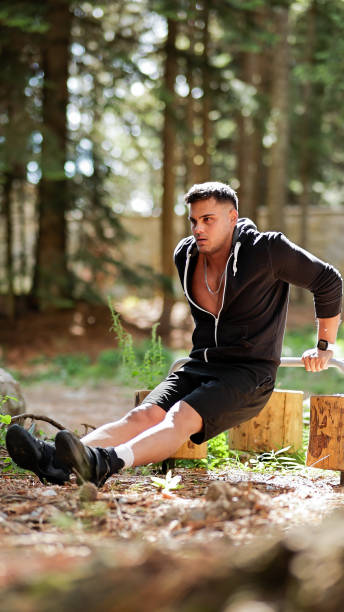 istock Young Man Practicing Tricep Dips on Parallel Bars in a Forested Outdoor Environment, Strength Training and Fitness Routine 2178050281