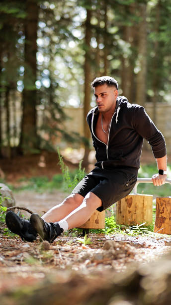 istock Young Man Practicing Tricep Dips on Parallel Bars in a Forested Outdoor Environment, Strength Training and Fitness Routine 2178050282