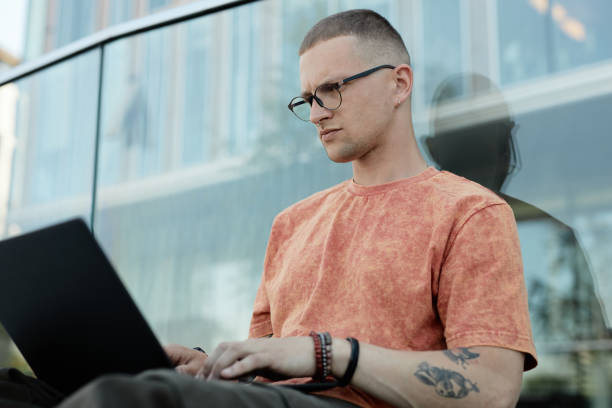 istock Frowning Man Using Laptop to Work while Sitting Outdoors in City 2178051893