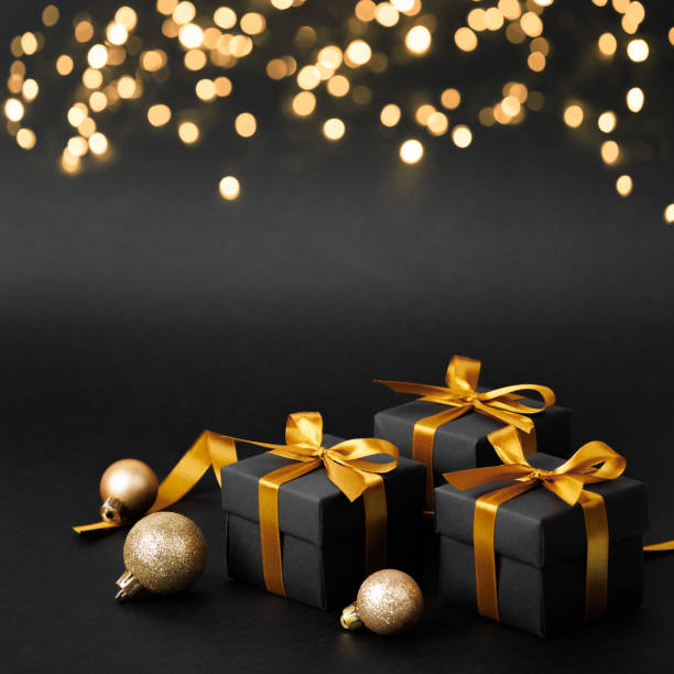 istock Three black gifts with gold bows on a black background 2178053976