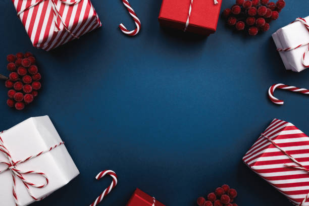 istock A circle of presents, candy canes, and berries on blue 2178054495