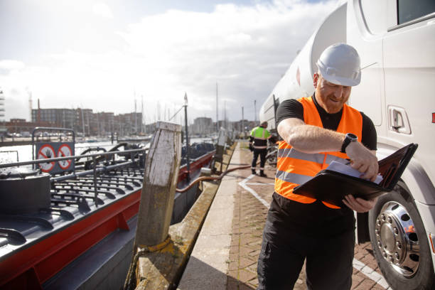 Shot of a young man in workwear using a digital tablet while standing on a large commercial dock