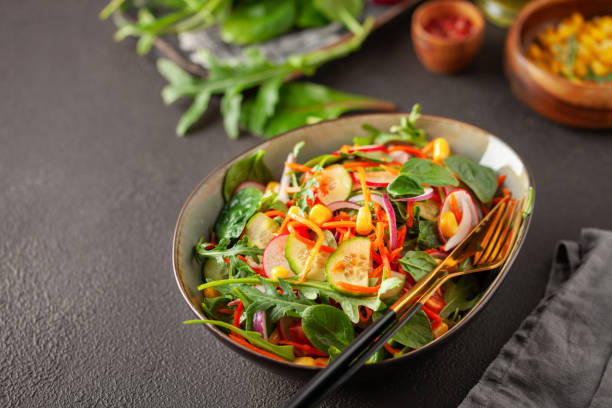 istock Fresh salad with vegetables. Arugula, spinach, cucumbers, tomato, onions carrots, corn andradishes in a plate on the table. Diet nutrition.  Copy space 2178078190