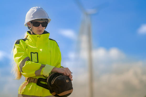 istock An engineer in high visibility work gear and a hard hat points toward a wind turbine in the background. The scene highlights renewable energy and the professional's involvement in wind farm operations. 2178082713