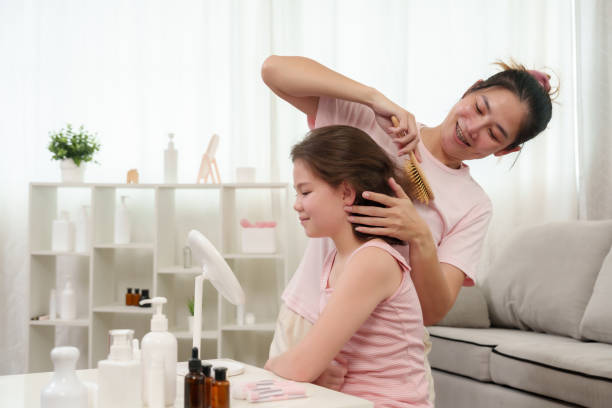 istock Mother happily brushes daughter's hair, both smiling warmly in a cozy home setting. Scene highlights nurturing care and close bond between mother and daughter, with soft natural light. 2178096261