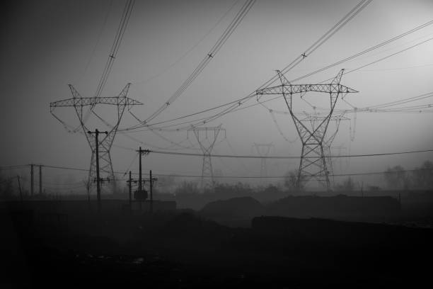 Abstract pattern from bottom view of high voltage pole power transmission tower with clear sky sunny day background in monochrome tone. Green energy, environmental conservation concept.
