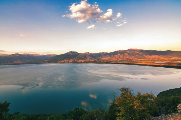 A panoramic view of Lake Prespa, located at the tripoint of North Macedonia, Albania, and Greece, surrounded by mountains and clear blue water.