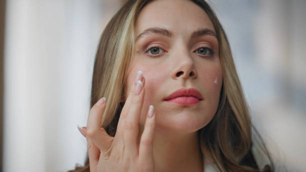istock Pov view woman moisturizing face with cream indoors. Model looking at camera 2178103722