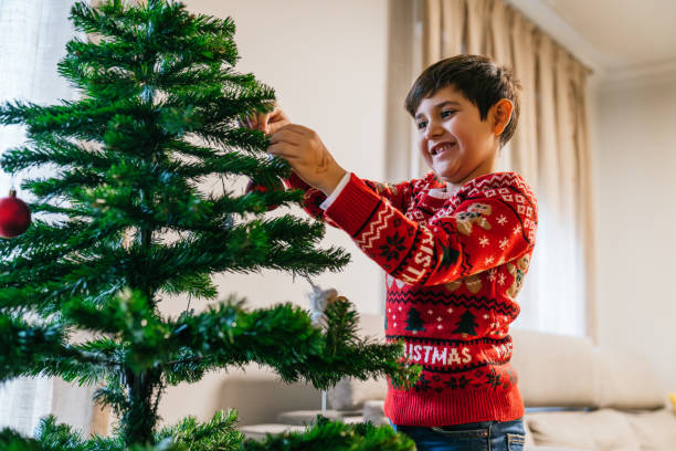 istock A young boy is decorating a Christmas tree with ornaments 2178105030
