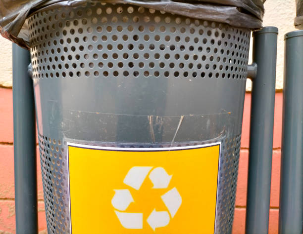 urban trash can with yellow recycling logo (plastics) close up