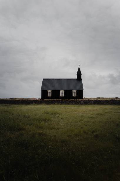 istock Solitary black church in a grassy field under cloudy sky 2178113047
