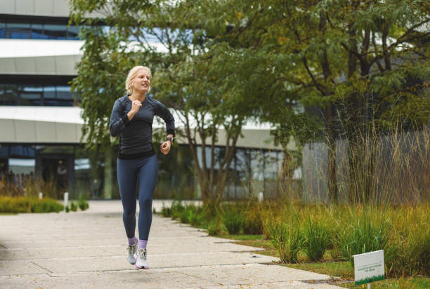 istock Jogging woman in urban greenery setting and sidewalk 2178123269