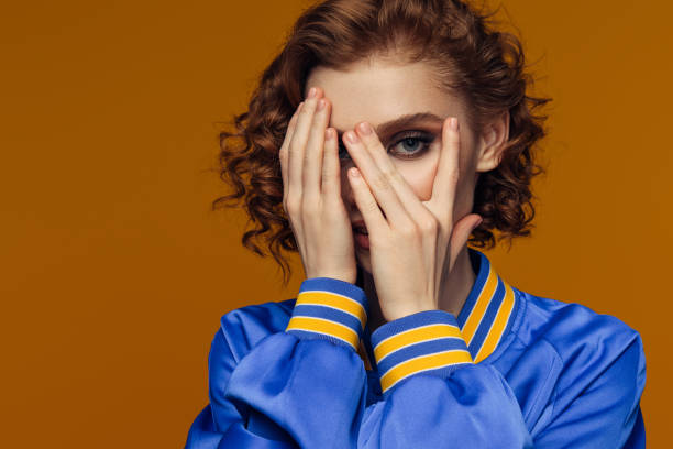 Redheaded Woman Peeking Through Fingers in Blue Jacket