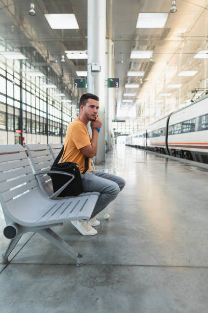 istock Blind young man waiting for train listening to announcement on platform 2178129431