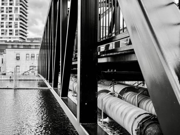 An industrial bridge over a canal in black and white.