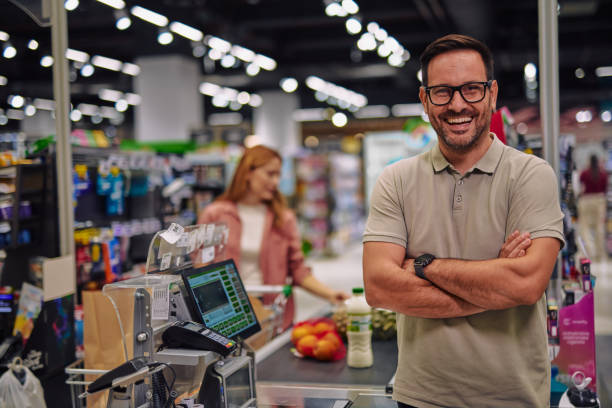istock Smiling Cashier in Supermarket with Customer in Background 2178134635