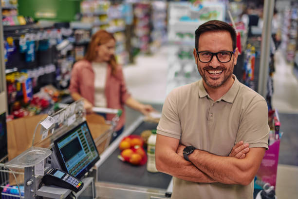 istock Smiling Cashier in Supermarket with Customer in Background 2178134642