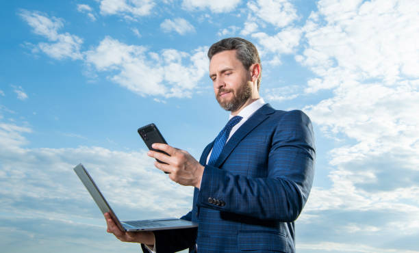 istock Successful businessman texting on mobile phone holding laptop. Mobile business communication 2178135569