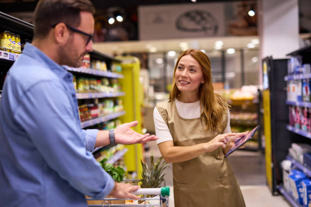 istock Man talking to female worker while shopping in supermarket 2178135614