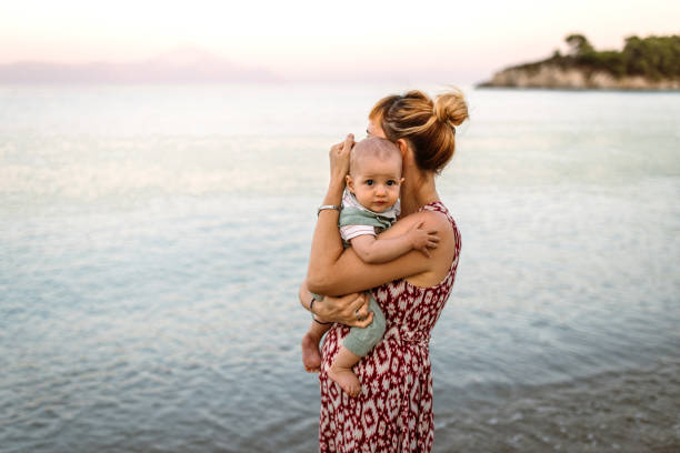Mid adult woman and her cute little baby boy sharing some affection and love at the beach