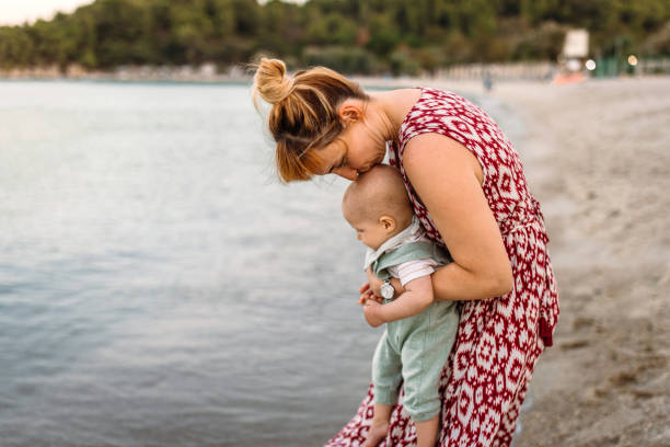 Mid adult woman and her cute little baby boy sharing some affection and love at the beach