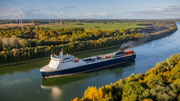istock Car ferry makes its way through the Kiel Canal, bordered by towering wind turbines, ground-mounted solar photovoltaic panels and colorful fall foliage. 2178142098