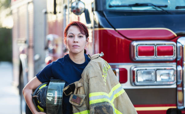 istock Female firefighter carrying protective gear by firetruck 2178143610