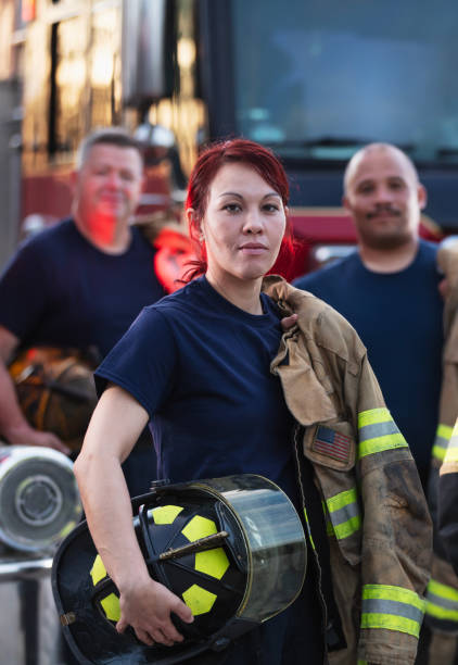 istock Female firefighter and group of firemen with fire trucks 2178143619