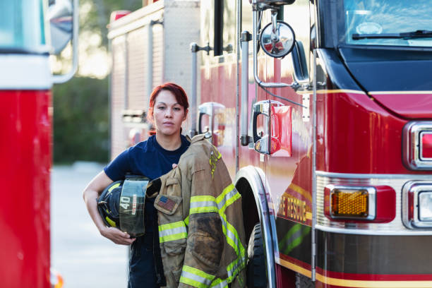 istock Female firefighter carrying protective gear by firetruck 2178143626