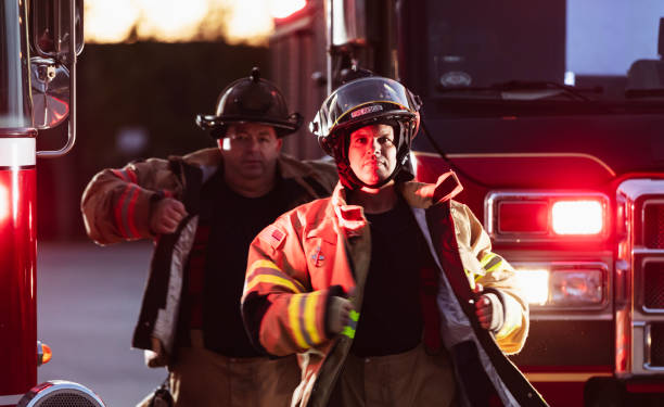 istock Two firefighters with firetruck, put on protective gear 2178143629