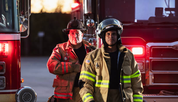 istock Two firefighters with firetruck, put on protective gear 2178143630