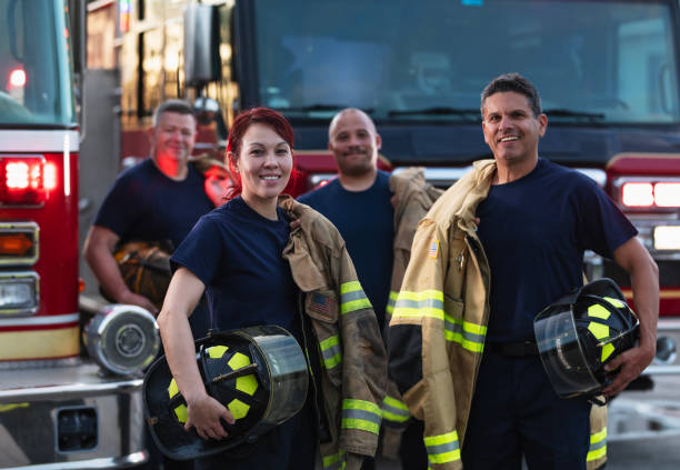 istock Female firefighter and group of firemen with fire trucks 2178143631