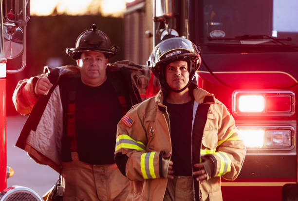 istock Two firefighters with firetruck, put on protective gear 2178143632