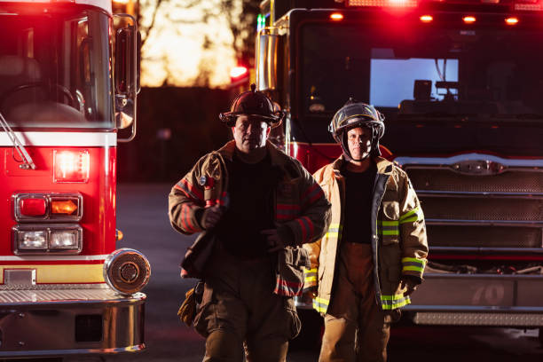 istock Two firefighters with firetruck, put on protective gear 2178143636