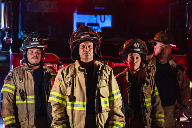 istock Multiracial group of firefighters by firetrucks at night 2178143659