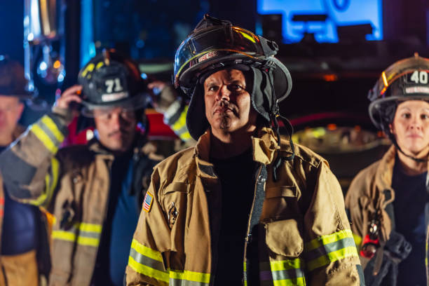 istock Multiracial group of firefighters by firetrucks at night 2178143677