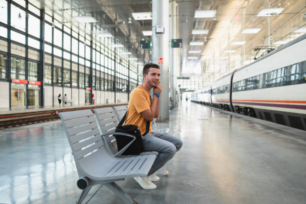 Blind young man talking on phone while waiting for train in station