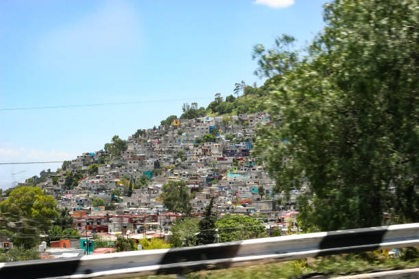 Crumbling concrete square buildings on the outskirts of Mexico City, built into the side of hills The suburbs on the outskirts of Mexico City are characterized by crumbling concrete square buildings precariously built into the sides of steep hills. These weathered architectural structures form dense, stacked residential areas, reflecting the urban sprawl and informal housing common in the region poverty mexico environment slum stock pictures, royalty-free photos & images