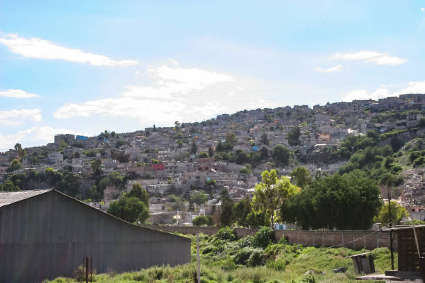 Crumbling concrete square buildings on the outskirts of Mexico City, built into the side of hills The suburbs on the outskirts of Mexico City are characterized by crumbling concrete square buildings precariously built into the sides of steep hills. These weathered architectural structures form dense, stacked residential areas, reflecting the urban sprawl and informal housing common in the region poverty mexico environment slum stock pictures, royalty-free photos & images