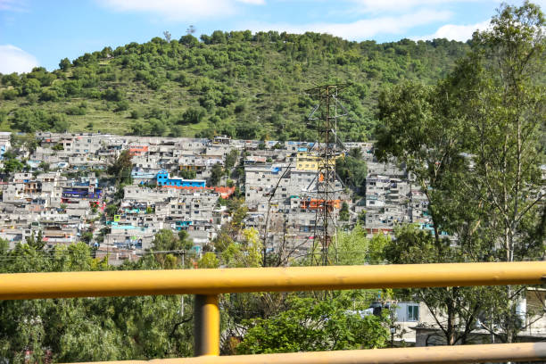 Crumbling concrete square buildings on the outskirts of Mexico City, built into the side of hills The suburbs on the outskirts of Mexico City are characterized by crumbling concrete square buildings precariously built into the sides of steep hills. These weathered architectural structures form dense, stacked residential areas, reflecting the urban sprawl and informal housing common in the region poverty mexico environment slum stock pictures, royalty-free photos & images