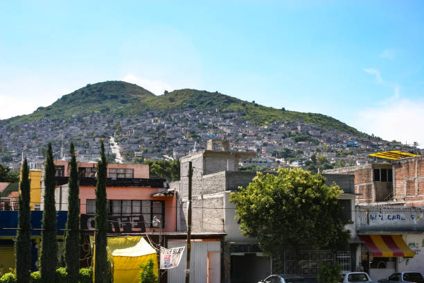Crumbling concrete square buildings on the outskirts of Mexico City, built into the side of hills The suburbs on the outskirts of Mexico City are characterized by crumbling concrete square buildings precariously built into the sides of steep hills. These weathered architectural structures form dense, stacked residential areas, reflecting the urban sprawl and informal housing common in the region poverty mexico environment slum stock pictures, royalty-free photos & images
