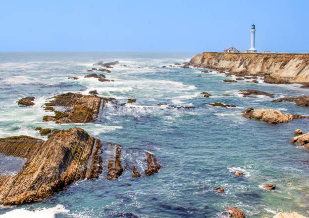 Pigeon Point Lighthouse in the distance along the rocky shore of the Northern California coast.  This is the tallest lighthouse on the West Coast of the United States.Taken from Pigeon Point Light Station State Historic Park