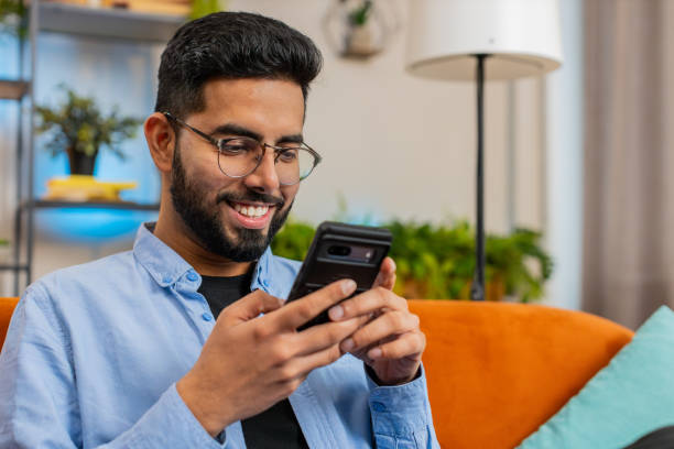 istock Happy Indian man thinking texting messaging on smartphone internet social media app on home sofa 2178147261